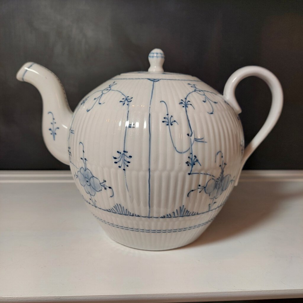 White teapot with blue floral patterns on a dark background