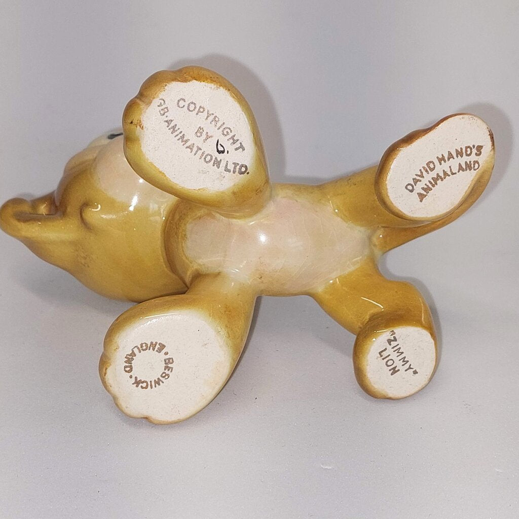 This is a David Hand's ZIMMY LION 1150 of Animaland Series by Beswick England. 1949-1955
The ZIMMY LION figurine is one of eight characters in David Hand's Animaland character series.
The figurine is 3-1/4 inches (8.25cm) tall.  
The backstamp is gold and reads: David Hand's Animaland, "Zimmy Lion 1150" Beswick England 6, Copyright by GB Animations Ltd.