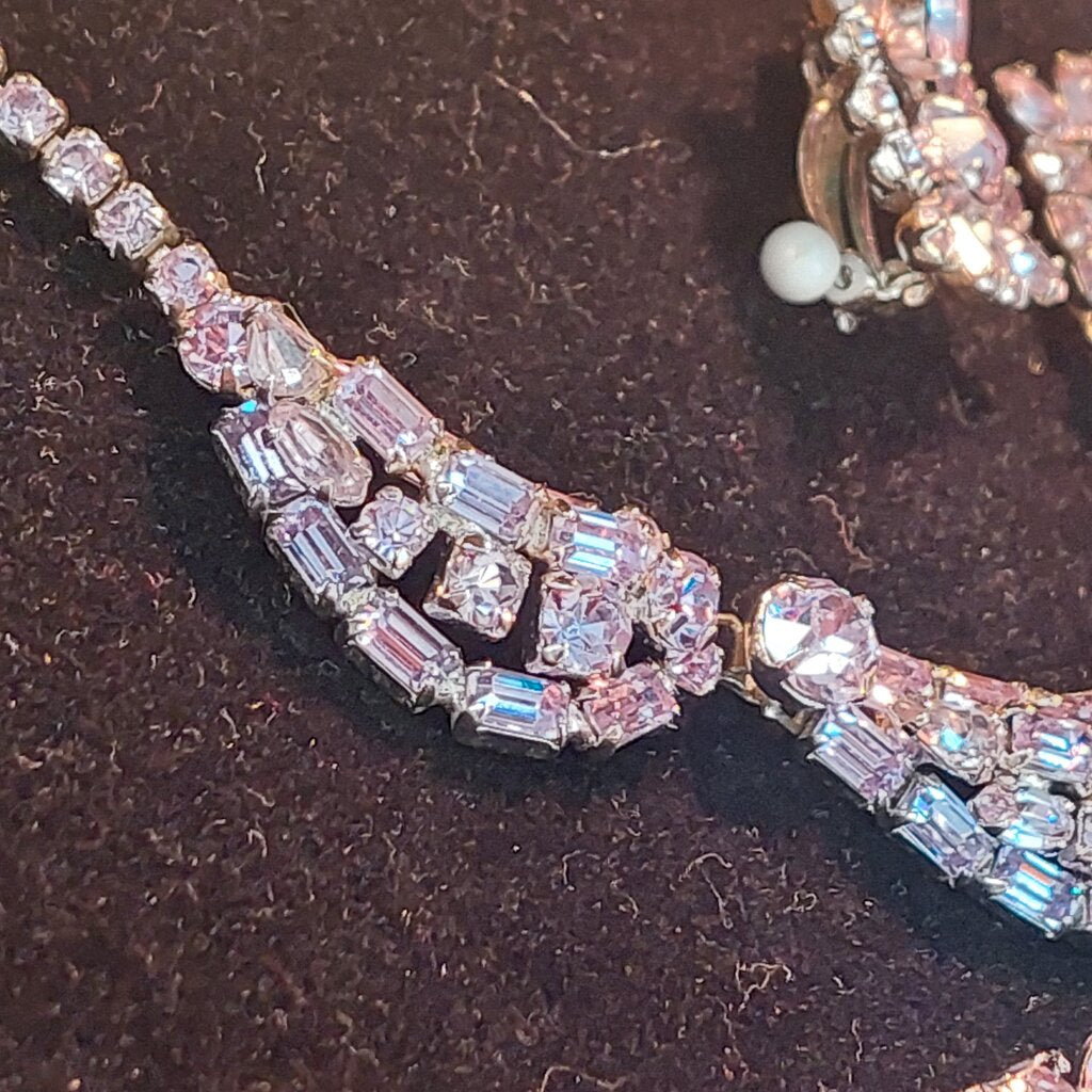This is a rare vintage 1950s Sherman necklace, clip on earrings, and brooch set in an amazing mauve colour. The crystals are a unique mix of baguette, marquise, round, and teardrop cuts. The 4 piece set comes in their original hinged box.