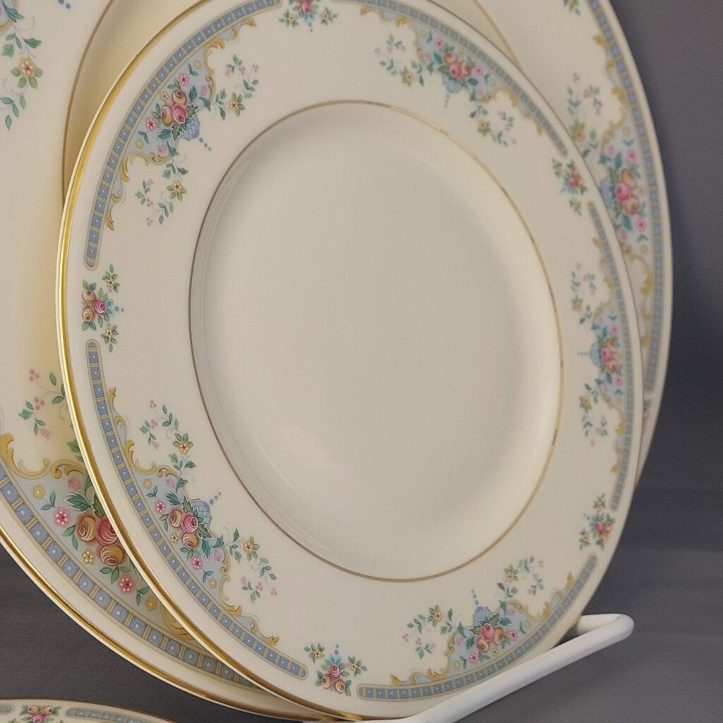 Set of decorative plates with floral patterns on a stand against a dark background