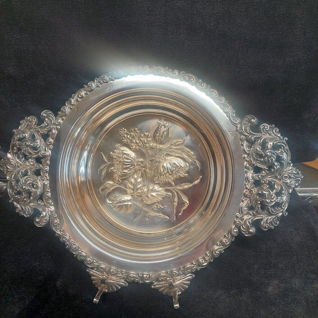 Decorative silver plate with floral design on a dark background