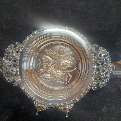 Decorative silver plate with floral design on a dark background