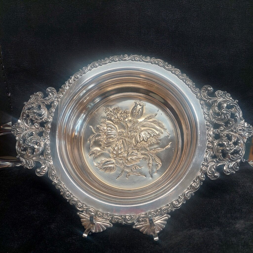 Decorative silver bowl with intricate designs on a black background