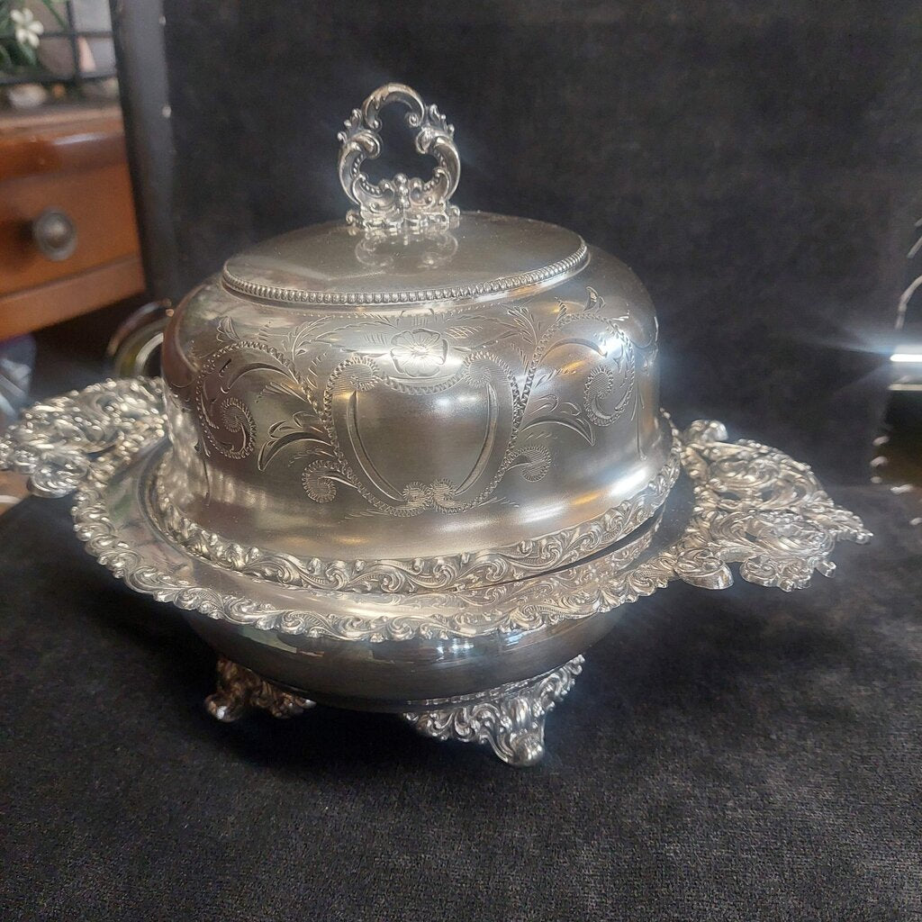 Decorative silver dish with intricate designs on a dark surface