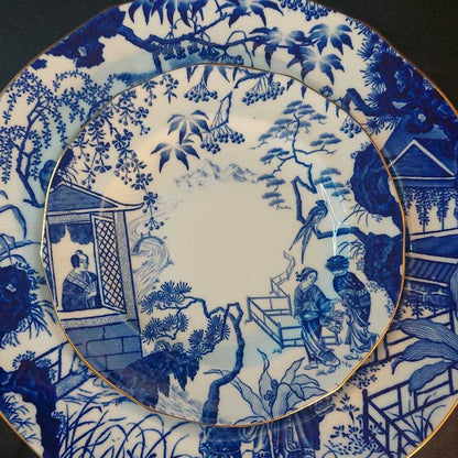 Blue and white ceramic plate with intricate design of people and landscape